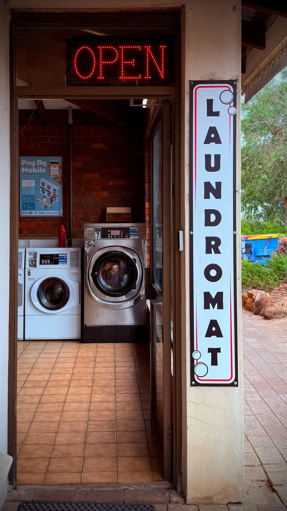 A row of laundromat machines — quarters, waiting, and someone else's schedule.